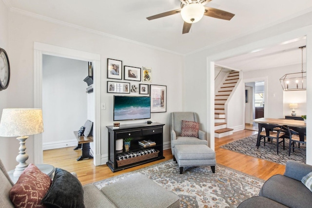 living room featuring wood finished floors, crown molding, stairs, and ceiling fan with notable chandelier