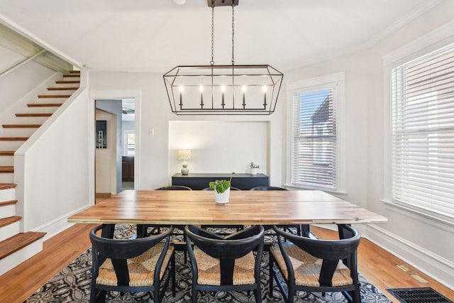 dining space featuring light wood-type flooring, visible vents, and stairs