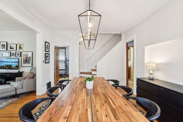dining space featuring baseboards, ornamental molding, wood finished floors, and stairs