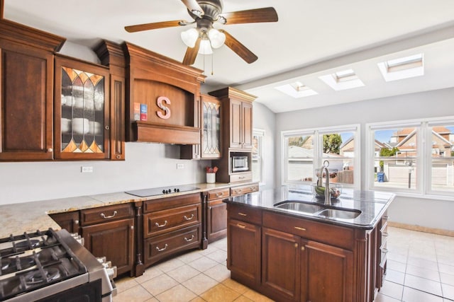kitchen featuring a sink, a skylight, light tile patterned floors, glass insert cabinets, and stainless steel appliances