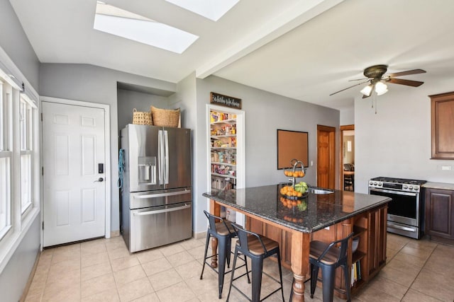 kitchen featuring a center island, a sink, a skylight, light tile patterned floors, and stainless steel appliances