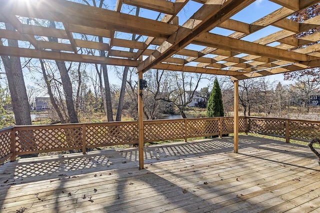 wooden deck with a water view and a pergola