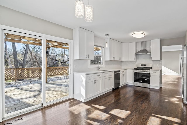 kitchen featuring stainless steel appliances, pendant lighting, white cabinets, and wall chimney exhaust hood