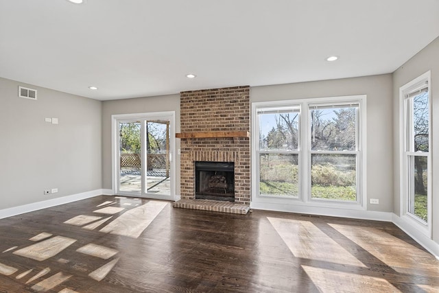 unfurnished living room with dark hardwood / wood-style flooring and a brick fireplace