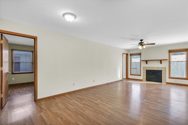 unfurnished living room featuring ceiling fan, light hardwood / wood-style floors, and a tiled fireplace