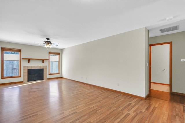 unfurnished living room with a tiled fireplace, ceiling fan, and light hardwood / wood-style flooring