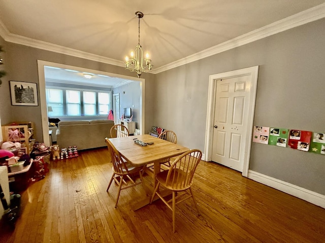 dining area with ornamental molding, wood-type flooring, and a notable chandelier