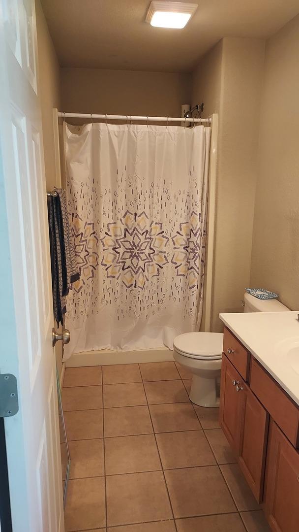 bathroom featuring toilet, vanity, tile patterned floors, and walk in shower