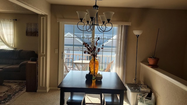 carpeted dining space featuring an inviting chandelier