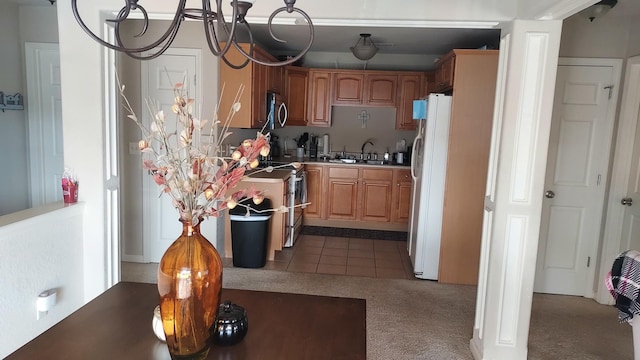 kitchen with carpet floors, stainless steel appliances, an inviting chandelier, and sink