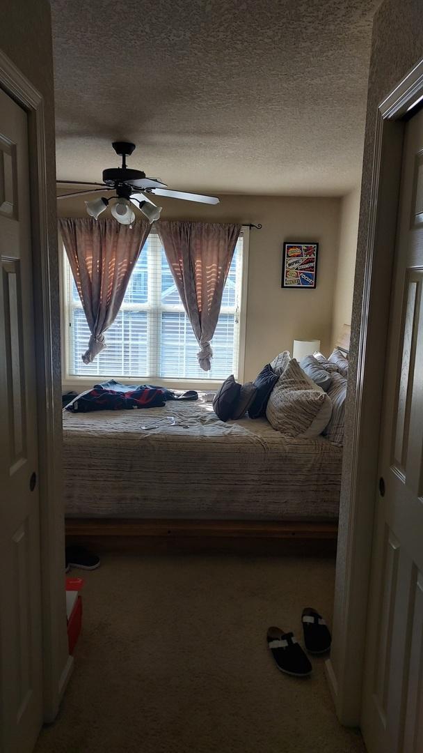 bedroom with carpet flooring, ceiling fan, a closet, and a textured ceiling