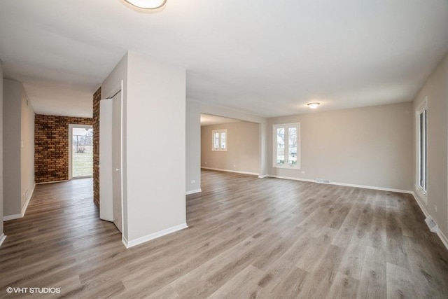 unfurnished room featuring light hardwood / wood-style floors and brick wall