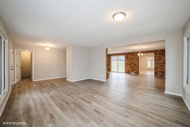 unfurnished living room featuring a brick fireplace, light hardwood / wood-style flooring, and brick wall