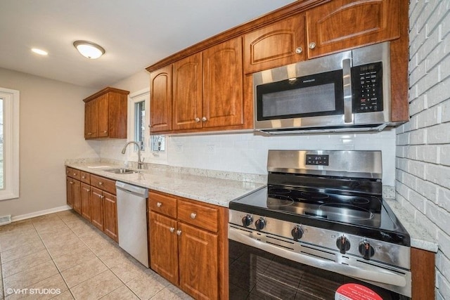 kitchen with sink, light tile patterned floors, light stone countertops, appliances with stainless steel finishes, and tasteful backsplash