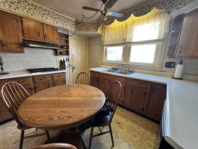 kitchen featuring ceiling fan, backsplash, stainless steel gas stovetop, and sink