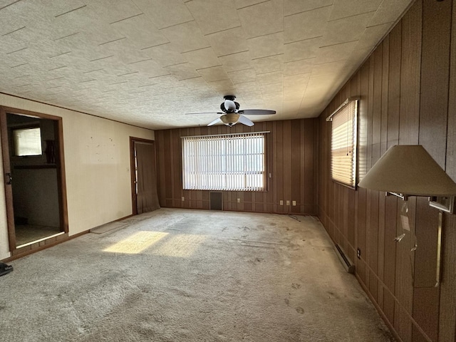 carpeted spare room featuring ceiling fan and wooden walls