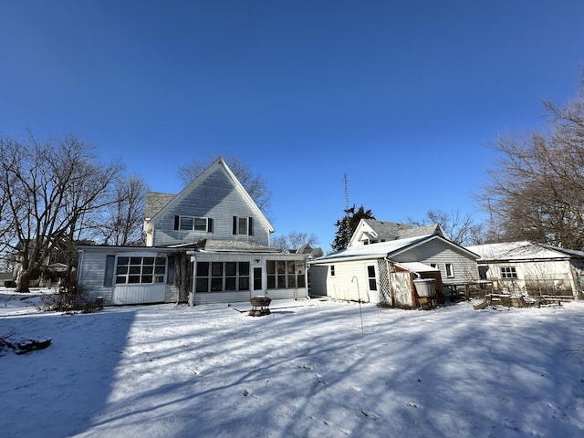 snow covered property with a sunroom and an outdoor fire pit