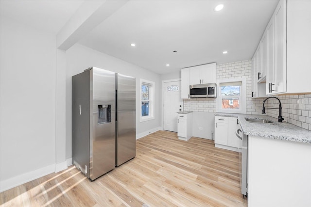 kitchen featuring decorative backsplash, sink, white cabinets, and stainless steel appliances