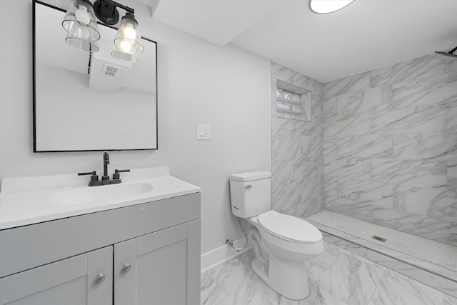 bathroom featuring a tile shower, vanity, and toilet