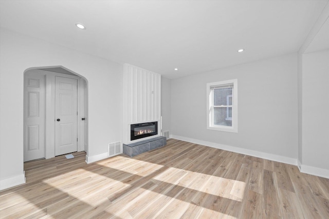 unfurnished living room featuring a large fireplace and light hardwood / wood-style floors