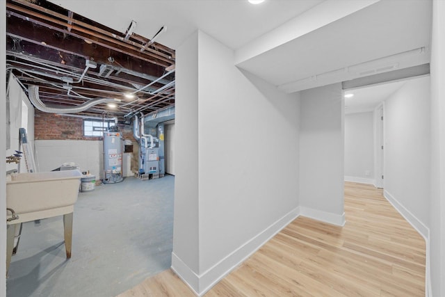 basement featuring heating unit, hardwood / wood-style floors, and gas water heater