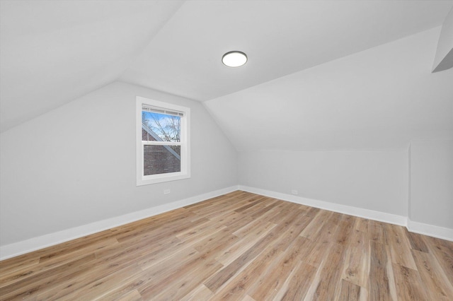 additional living space featuring light wood-type flooring and vaulted ceiling