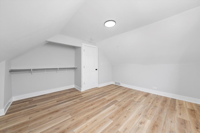 additional living space with light wood-type flooring and vaulted ceiling