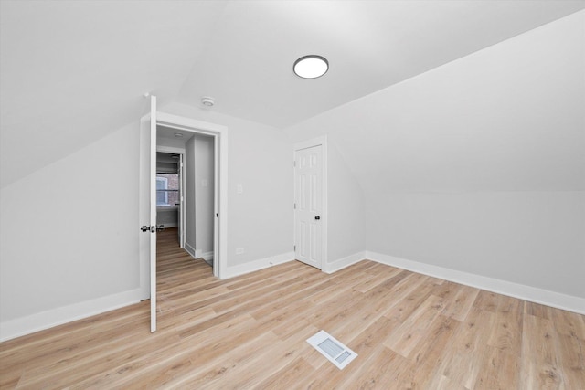 additional living space featuring vaulted ceiling and light wood-type flooring