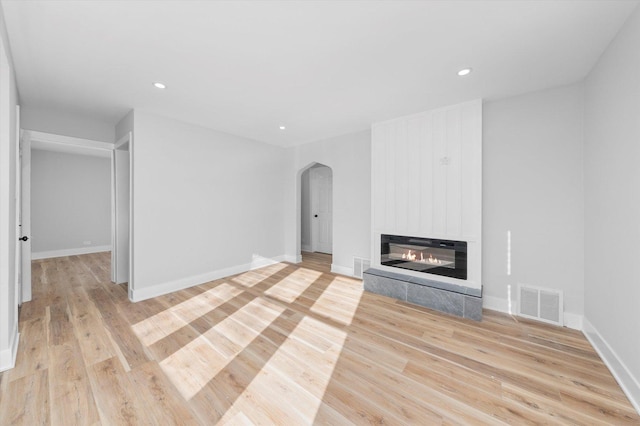 unfurnished living room with a fireplace and light wood-type flooring