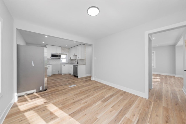 unfurnished living room featuring sink and light wood-type flooring