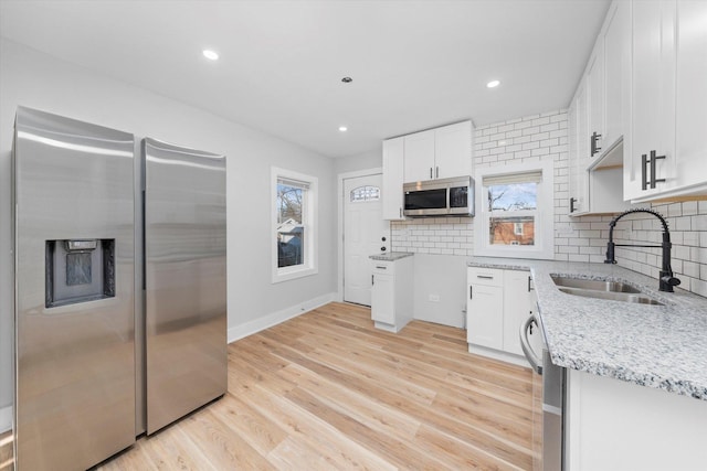 kitchen with white cabinets, sink, stainless steel appliances, and tasteful backsplash