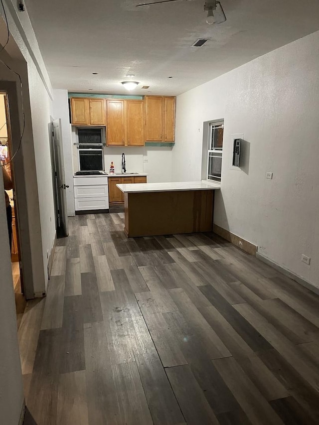 kitchen featuring kitchen peninsula, dark hardwood / wood-style floors, sink, and black oven