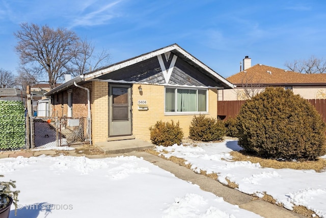 bungalow-style house featuring brick siding and fence