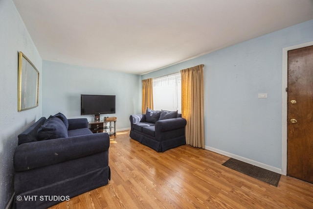 living area featuring baseboards and light wood finished floors