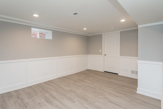 basement with crown molding and light hardwood / wood-style flooring