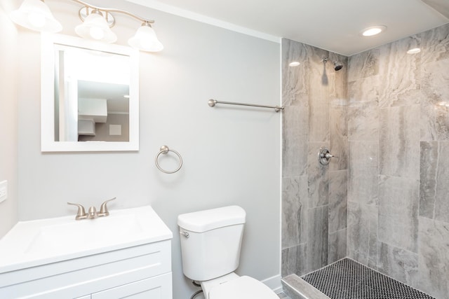 bathroom with a tile shower, vanity, and toilet