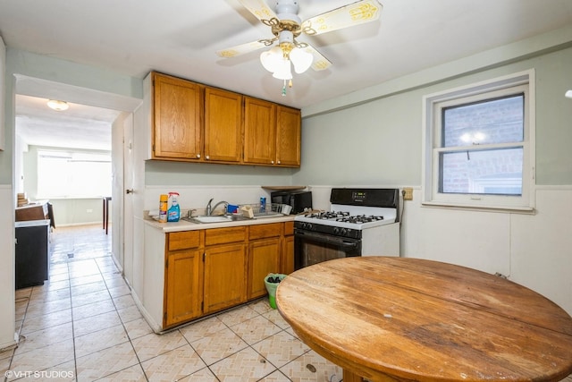 kitchen featuring sink, ceiling fan, gas range gas stove, and light tile patterned floors