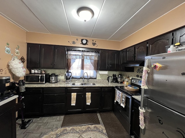 kitchen with light stone counters, sink, and appliances with stainless steel finishes