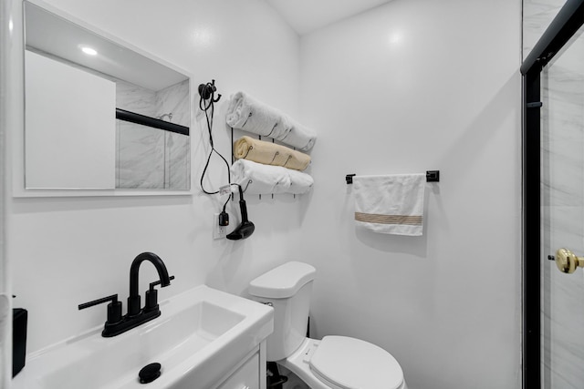 bathroom with vanity, toilet, and a shower with door