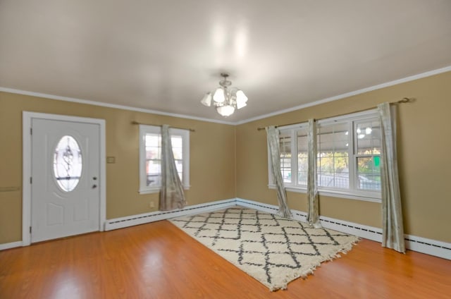 entryway featuring baseboard heating, hardwood / wood-style flooring, ornamental molding, and an inviting chandelier