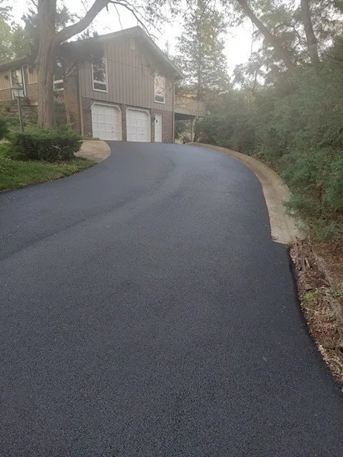 view of property exterior with aphalt driveway, brick siding, board and batten siding, and an attached garage