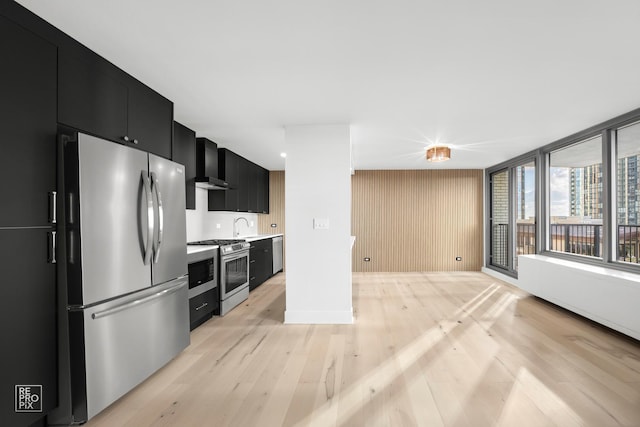 kitchen featuring appliances with stainless steel finishes, sink, light hardwood / wood-style floors, and wall chimney range hood