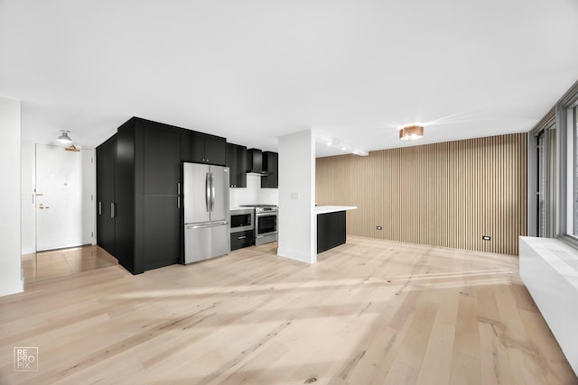 kitchen featuring wall chimney exhaust hood, light hardwood / wood-style floors, and appliances with stainless steel finishes