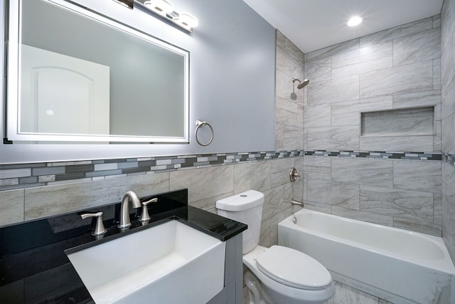 full bathroom featuring tile walls, vanity, tiled shower / bath combo, and toilet