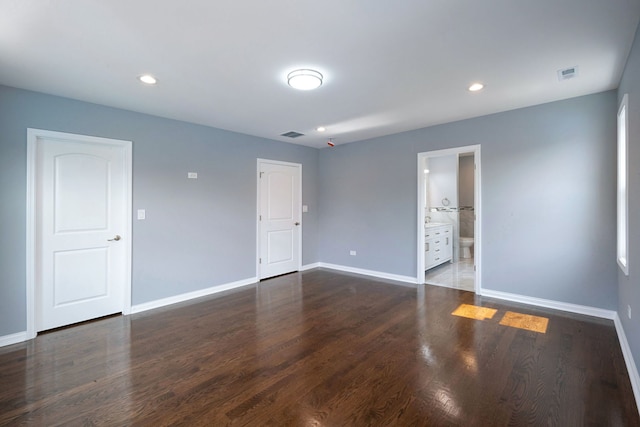 unfurnished bedroom featuring connected bathroom and dark wood-type flooring