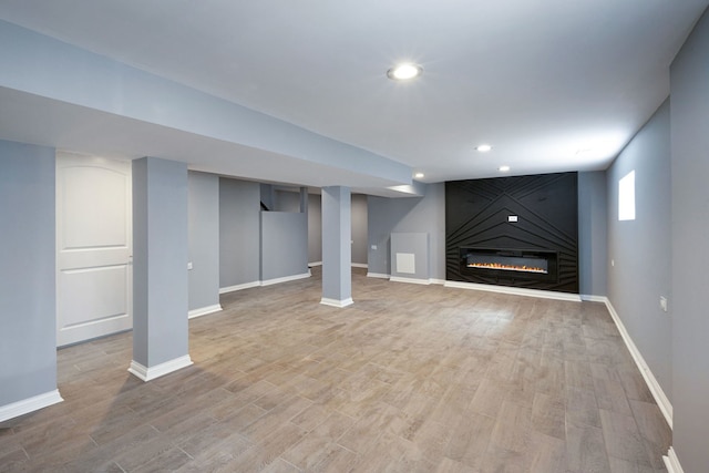 basement with a fireplace and light hardwood / wood-style floors