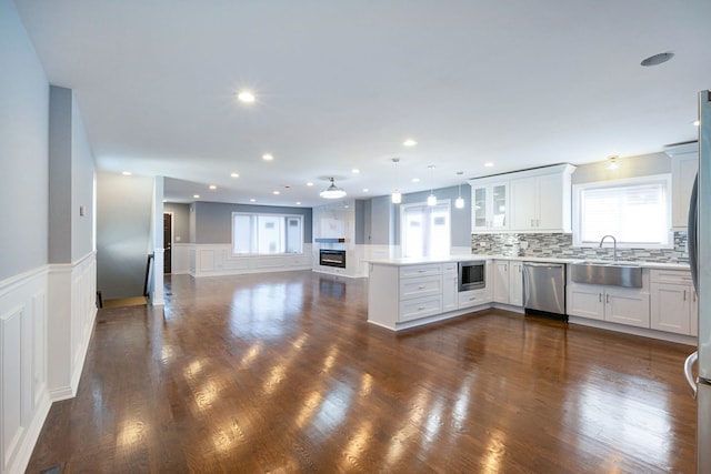 kitchen with kitchen peninsula, tasteful backsplash, stainless steel dishwasher, built in microwave, and sink