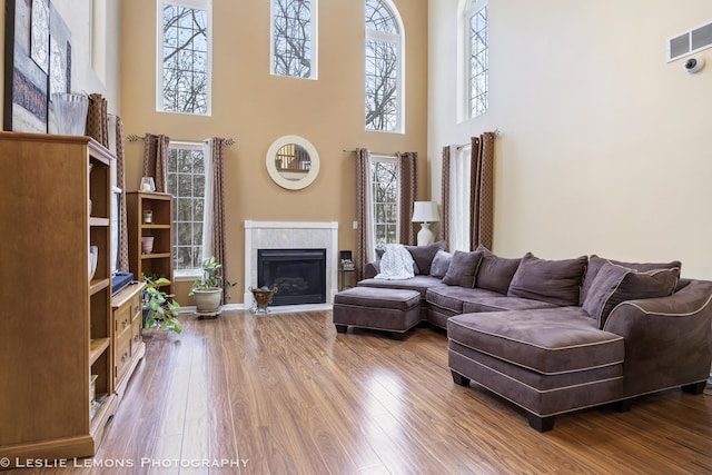 living room with a tiled fireplace, a high ceiling, and hardwood / wood-style flooring