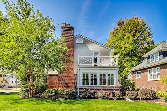 rear view of property with a yard and a balcony