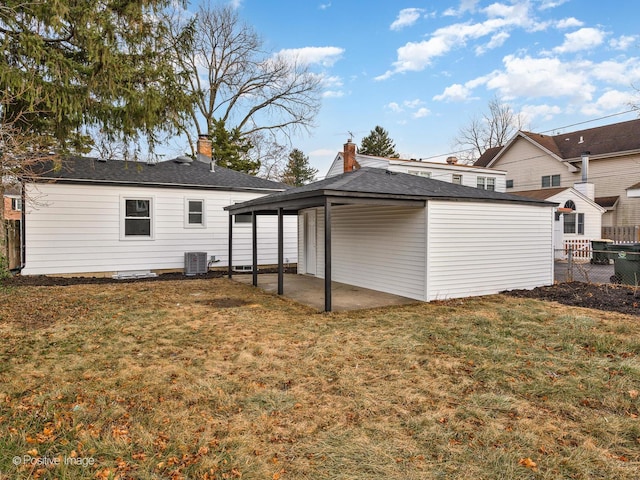 rear view of property featuring a lawn, cooling unit, and a patio area